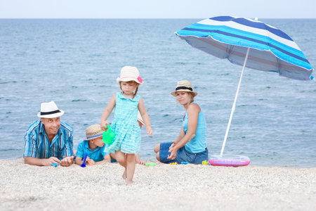 Happy family playing by the sea shore on the sand backgroundの写真素材
