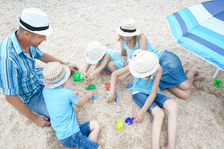 Happy family playing by the sea shore on the sand backgroundの写真素材
