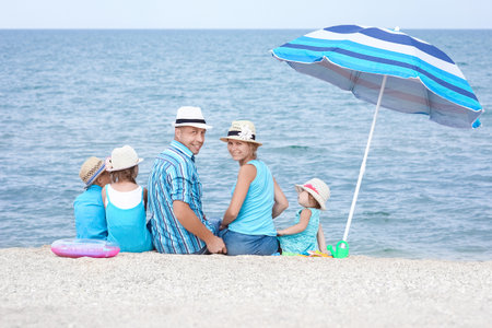 Happy family playing by the sea shore on the sand backgroundの写真素材