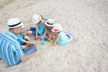 Happy family playing by the sea shore on the sand backgroundの写真素材