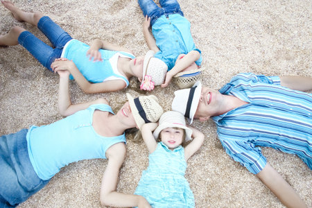 Happy family playing by the sea shore on the sand backgroundの写真素材