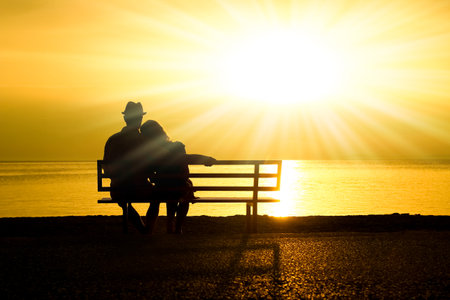 happy couple on a bench by the sea on nature in travel silhouetteの写真素材