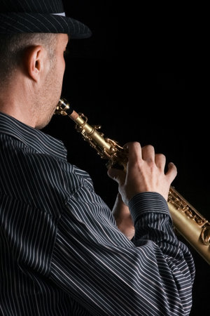 soprano saxophone in the hands of a guy on a black backgroundの写真素材