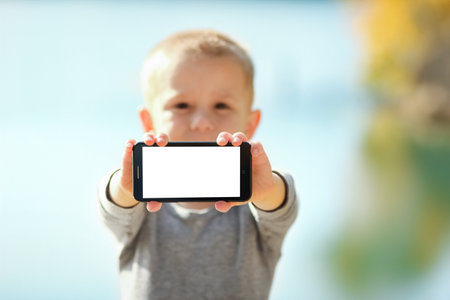 Happy child with phone taking selfie in nature in the park travelの写真素材
