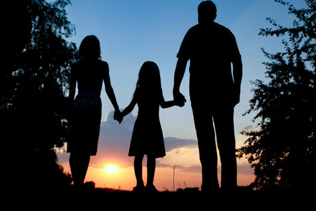 Happy family together at sunset silhouetteの写真素材