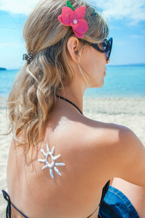 happy girl on the sea with a picture of the sun on her backの写真素材