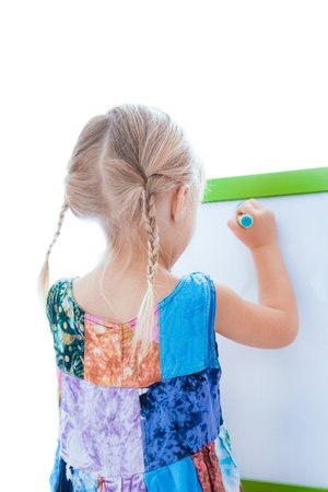 happy child draws on easel on a white backgroundの写真素材