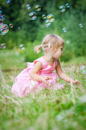 happy little girl chasing bubbles on nature in the parkの写真素材