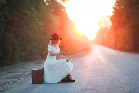 vintage girl with hat with a suitcase hitchhikingの写真素材