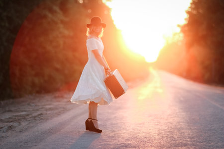 vintage girl with hat with a suitcase hitchhikingの写真素材