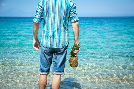 happy man with a pineapple in his hands near the sea in nature weekend travelの写真素材