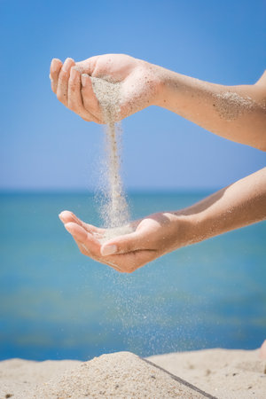 Hands pour sand off the sea on nature on a journey. Vacations at sea sand time passes.の写真素材