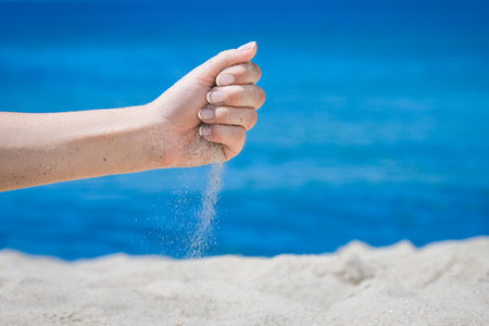 Hands pour sand off the sea on nature on a journey. Vacations at sea sand time passes.の写真素材