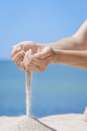 Hands pour sand off the sea on nature on a journey. Vacations at sea sand time passes.の写真素材