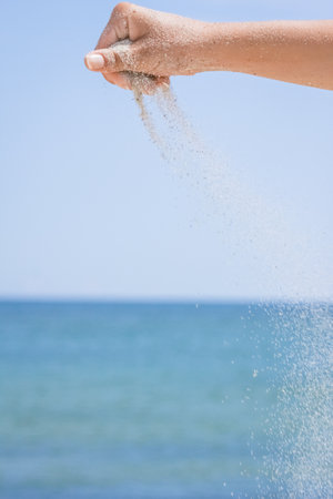 Hands pour sand off the sea on nature on a journey. Vacations at sea sand time passes.の写真素材