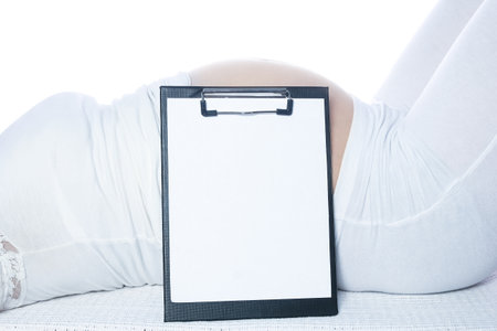 Happy pregnant girl lies on white backgroundの写真素材