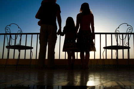 Happy family at the dawn of the sea silhouette backgroundの写真素材