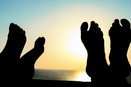 Beautiful legs at the dawn silhouette of the sea backgroundの写真素材