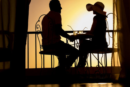 Couple man and woman silhouette on a balcony by the sea on the background. Meeting in a double date on the terrace.の写真素材