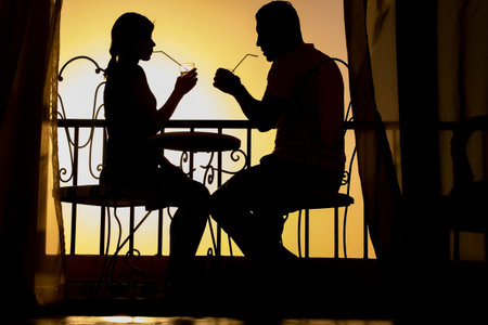 Couple man and woman silhouette on a balcony by the sea on the background. Meeting in a double date on the terrace.の写真素材