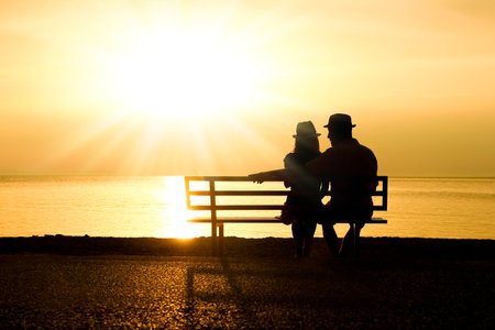 happy couple on a bench by the sea on nature in travel silhouetteの写真素材
