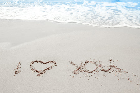 beautiful drawings inscription on the sand of the sea in the summer on the natureの写真素材