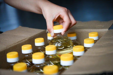 Hand with many bottles of sunflower oil in boxの写真素材