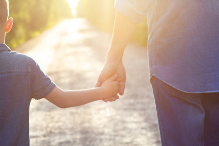 Hands of a happy parent and child in nature in the travel parkの写真素材