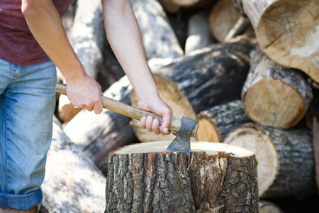man chopping wood with an ax country backgroundの写真素材