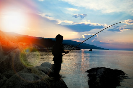 happy child fishing by the sea silhouetteの写真素材