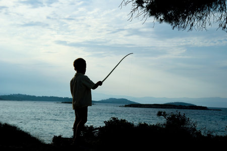 happy child fishing by the sea silhouetteの写真素材