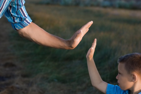 Hands of a happy child and parent in nature in a park by the roadの写真素材