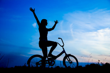 Happy girl on bike concept in park on nature travel silhouetteの写真素材