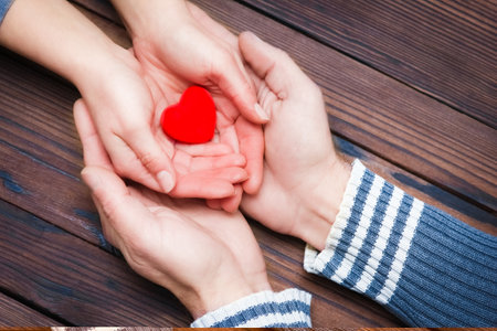 A Heart in hands on valentine's day on a wooden backgroundの写真素材