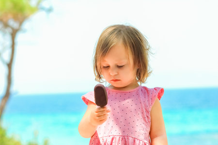 Happy child girl with ice cream by the sea in nature in the park journeyの写真素材