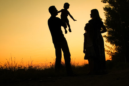 silhouette of a happy family on the nature of the sunset in the parkの写真素材