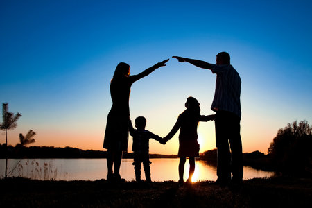 silhouette family, including his father, mother and two children in the hands ofの写真素材