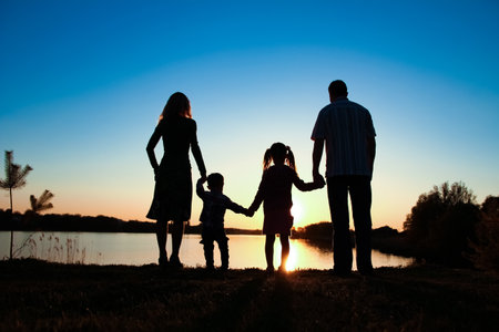 silhouette family, including his father, mother and two children in the hands ofの写真素材