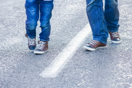 Beautiful feet of parent and child on the road in the park on nature travel
