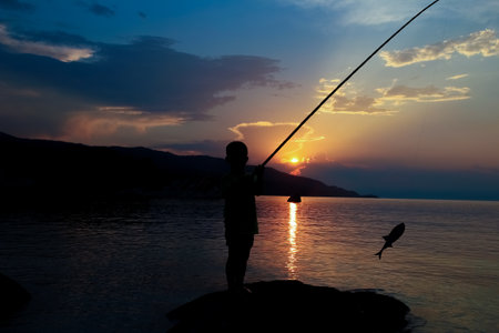 happy child fishing by the sea silhouetteの写真素材
