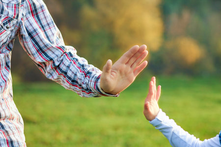 hands of parent and child outdoors in the parkの写真素材