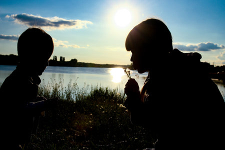Happy children silhouettes on sunset backgroundの写真素材
