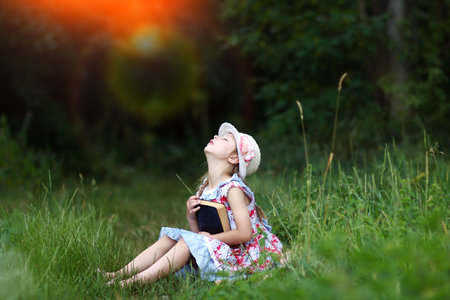 little girl reading bible book outdoorsの写真素材
