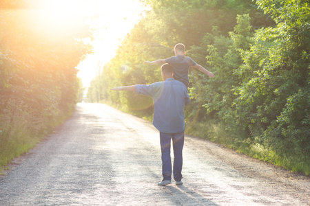 Happy child on the shoulders of a parent in nature on the way to travelの写真素材