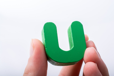 Hand holding letter cube U of made of woodの写真素材