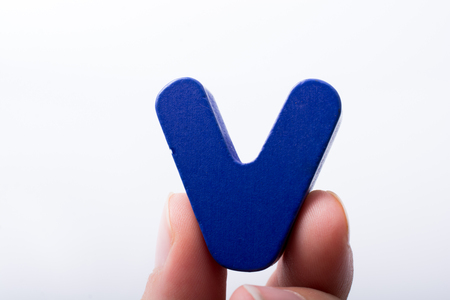 Hand holding letter cube V of made of woodの写真素材