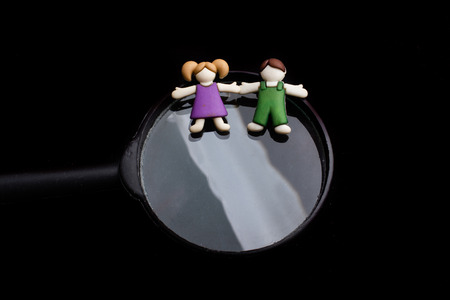 Boy and girl figurine on magnifying glass  as people conceptの写真素材