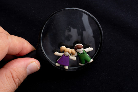 Boy and girl figurine on magnifying glass  as people concept