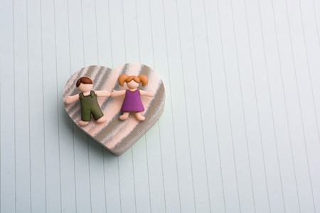 Boy girl figurine on a Heart shape as love conceptionの写真素材