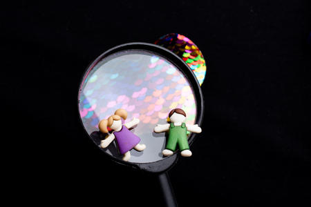 Boy and girl figurine on a magnifying glass and heartの写真素材
